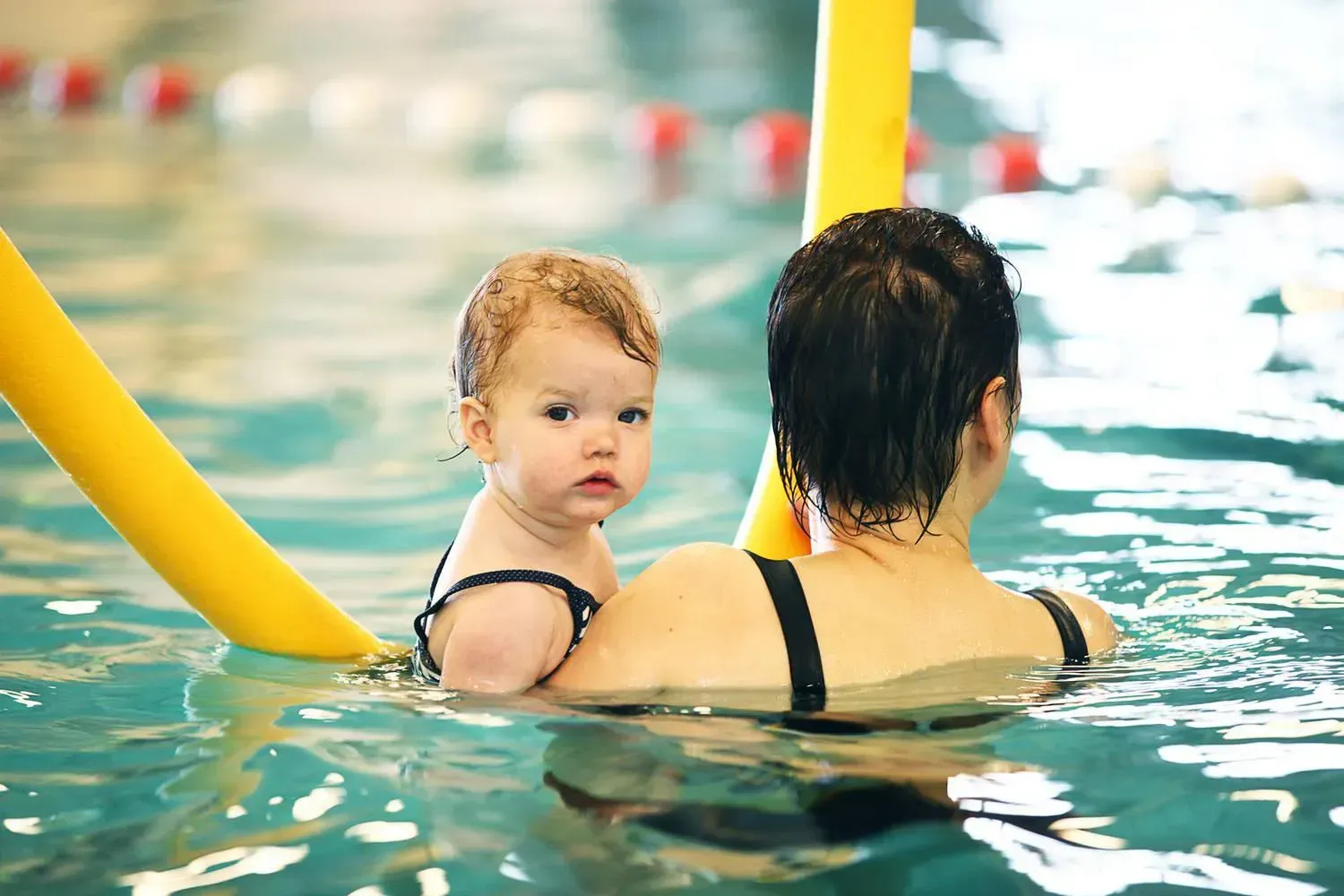 vrouw met kind in zwembad met gele zwemworst