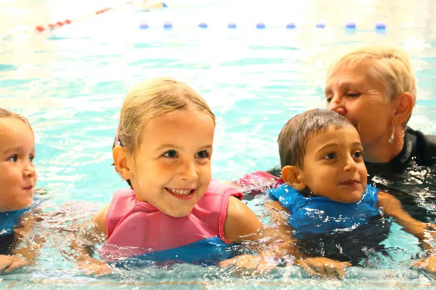 Lachende kinderen in zwembad met juffrouw