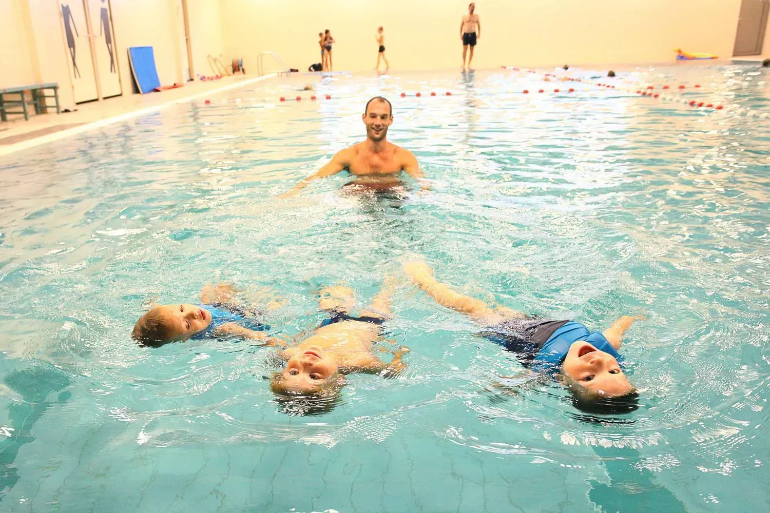 zwemleraar met drie kinderen, zwemles, easyswim, blauw water